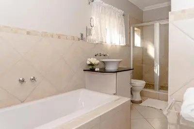 a bathroom with a tub and a toilet and a sink at Bela Rini Guesthouse in Bela-Bela