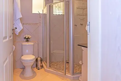 a bathroom with a shower and a toilet at Bela Rini Guesthouse in Bela-Bela