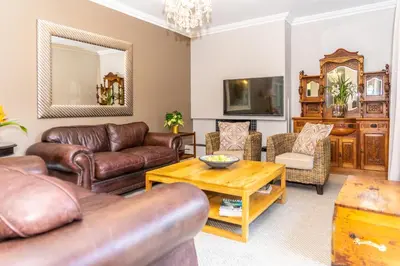 a living room with leather furniture and a table at Bela Rini Guesthouse in Bela-Bela