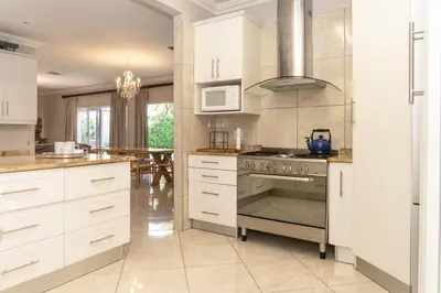 a kitchen with white cabinets and a stove top oven at Bela Rini Guesthouse in Bela-Bela