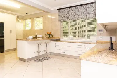 a kitchen with white cabinets and marble counter tops at Bela Rini Guesthouse in Bela-Bela