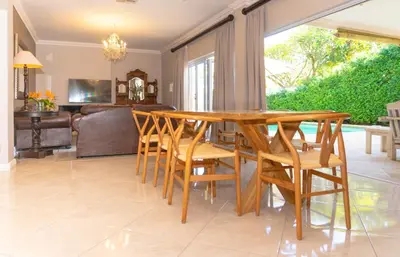 a dining room with a table and chairs and a couch at Bela Rini Guesthouse in Bela-Bela