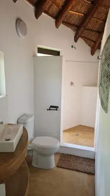 a white bathroom with a toilet and a shower at Milkwood Valley Lodge, Mabalingwe in Bela-Bela