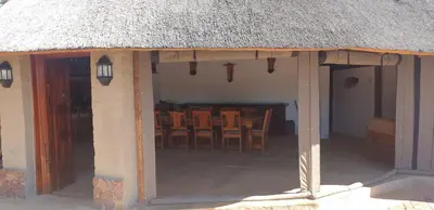 a house with a thatched roof with chairs and tables at Milkwood Valley Lodge, Mabalingwe in Bela-Bela