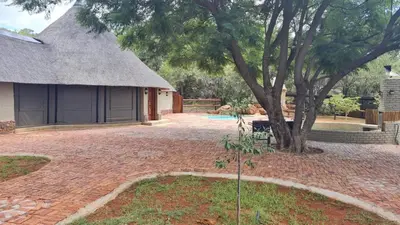 a house with a tree and a brick yard at Milkwood Valley Lodge, Mabalingwe in Bela-Bela