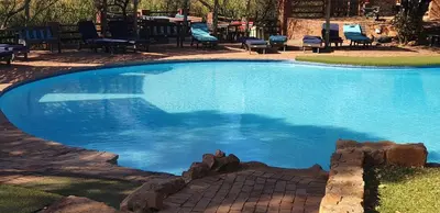 a large pool with blue water in a yard at Milkwood Valley Lodge, Mabalingwe in Bela-Bela