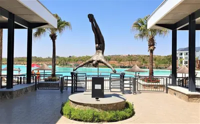 a statue of a dinosaur in front of a pool at THE BLYDE CRISTAL LAGOON in Pretoria
