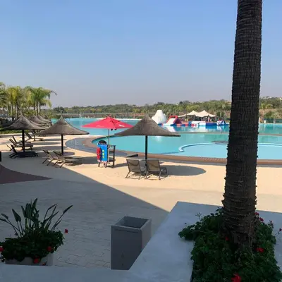 a resort with a pool with umbrellas and chairs at THE BLYDE CRISTAL LAGOON in Pretoria