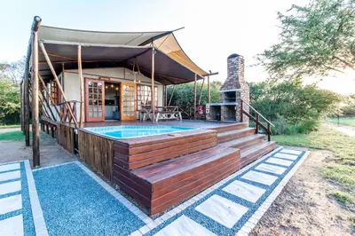 a house with a deck and a swimming pool at Jabula Bush Camp in Klipdrift