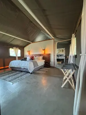 a bedroom with a bed and a table and chairs at Jabula Bush Camp in Klipdrift