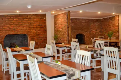 a restaurant with tables and chairs and a brick wall at Franks Bush Camp in Hoedspruit