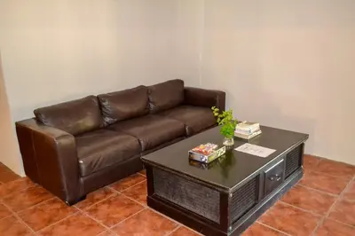a brown leather couch in a living room with a table at Franks Bush Camp in Hoedspruit