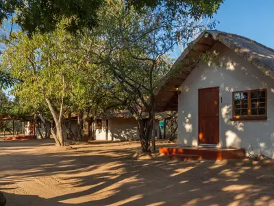 a small white house with a thatched roof at Franks Bush Camp in Hoedspruit