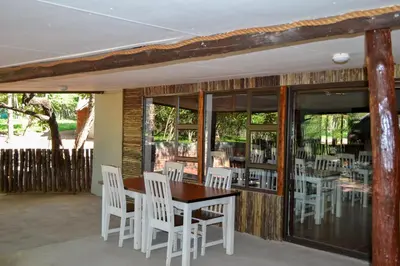 a dining room with white chairs and a wooden table at Franks Bush Camp in Hoedspruit
