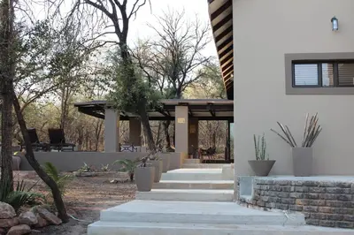 a house with stairs leading up to a porch at The Aloes Bush Lodge in Marloth Park