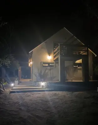 a small white house at night with lights at The Aloes Bush Lodge in Marloth Park