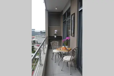 a kitchen with a table and chairs on a balcony at Furnished, 1-bedroom, luxury apartment in Menlyn Maine in Pretoria