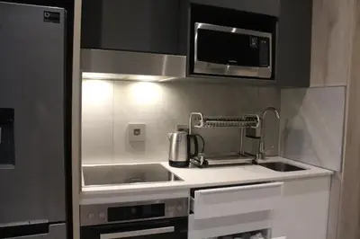 a small kitchen with a sink and a microwave at Furnished, 1-bedroom, luxury apartment in Menlyn Maine in Pretoria