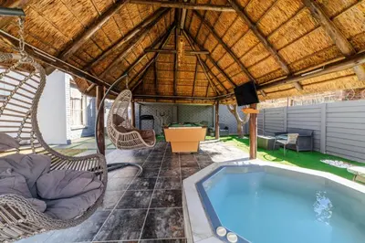 a patio with a hot tub and wicker chairs at Homes of Ace Executive in Pretoria
