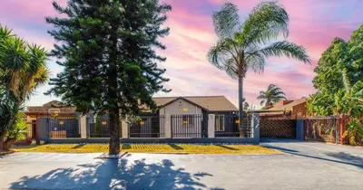 a house with palm trees and a fence at Homes of Ace Executive in Pretoria