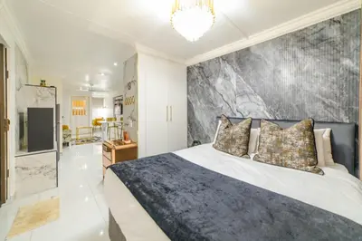 a bedroom with a king sized bed with a marble wall at Homes of Ace Executive in Pretoria