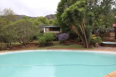 a large blue swimming pool in front of a house at Goederus Guest Farm in Sterkspruit