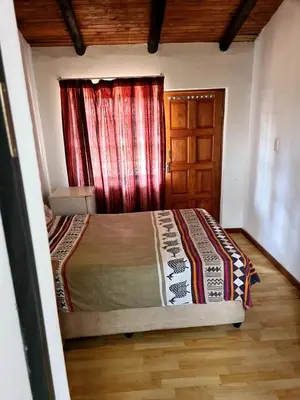 a bedroom with a bed with a red curtain and a window at Baraka House in Midrand