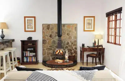 a living room with a stone fireplace and a couch at Tomjachu Bush Retreat in Nelspruit