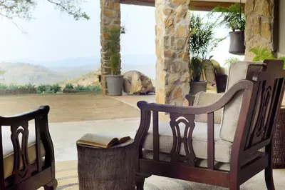 two wooden chairs sitting on a porch with a book at Tomjachu Bush Retreat in Nelspruit