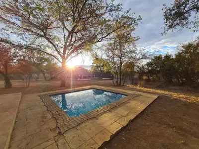 a swimming pool in a yard with a tree at Pumba's Place Zebula 6 Bedroom House in Mabula