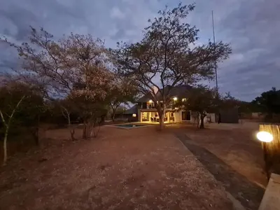 a house with a tree in the middle of a yard at Pumba's Place Zebula 6 Bedroom House in Mabula