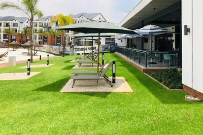 a group of benches with umbrellas on a lawn at The Blyde Unit 1321 in Pretoria