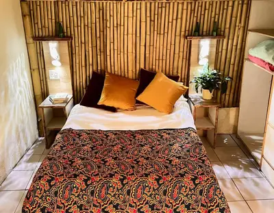 a bedroom with a large bed with orange pillows at Hazyview Adventure Backpackers in Hazyview