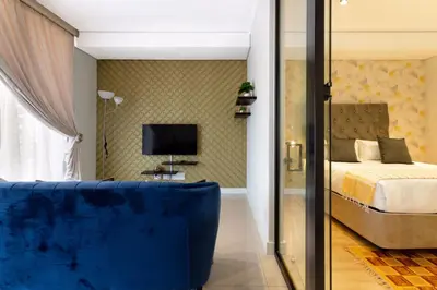 a bedroom with a bed and a blue couch at Alimama Spaces: The Chelsea's Ellipse in Midrand