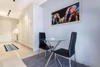 a dining room with a glass table and two chairs at Alimama Spaces: The Chelsea's Ellipse in Midrand