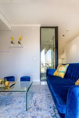 a living room with a blue couch and a glass table at Alimama Spaces: The Fountain Hill Ellipse in Midrand