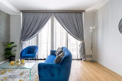 a living room with a blue couch and a large window at Alimama Spaces: The Manson's Ellipse in Midrand