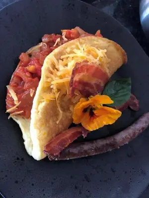 a sandwich with bacon and cheese on a plate at Absolut Guest Boutique in Centurion