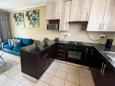 a kitchen with black cabinets and a blue couch at Tshamani self catering in Hazyview