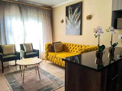 a living room with a yellow couch and a table at Tshamani self catering in Hazyview