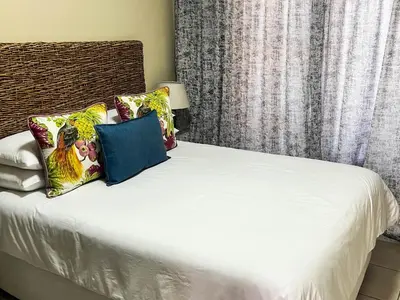 a bedroom with a bed with white sheets and pillows at Tshamani self catering in Hazyview