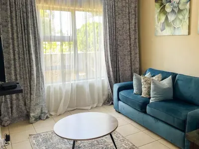 a living room with a blue couch and a table at Tshamani self catering in Hazyview