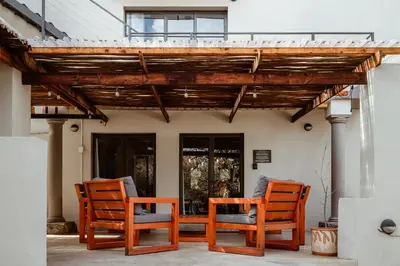 a patio with three chairs and a pergola at Jackals Dream - Self Catering Villa bordering Kruger National Park in Marloth Park