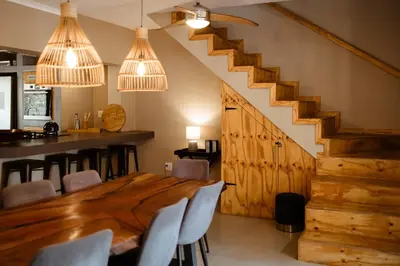 a dining room with a wooden table and a staircase at Jackals Dream - Self Catering Villa bordering Kruger National Park in Marloth Park