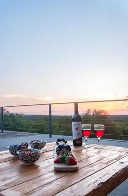 a bottle of wine and two glasses on a wooden table at Jackals Dream - Self Catering Villa bordering Kruger National Park in Marloth Park