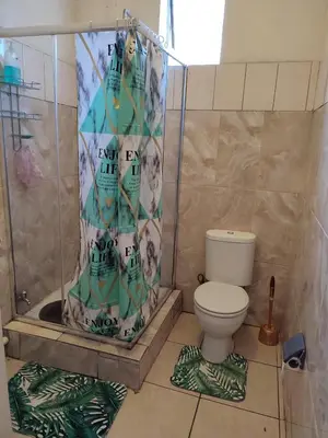a bathroom with a shower curtain with a toilet at The Croc Guest house in Springs