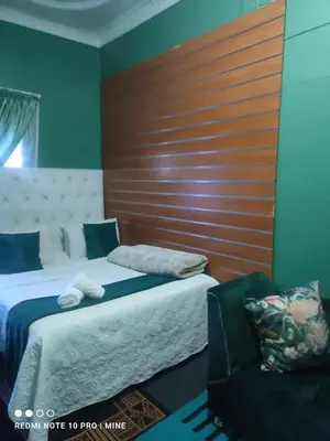a bedroom with two beds and a wooden wall at The Croc Guest house in Springs