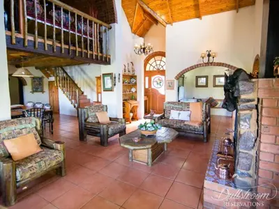 a living room with couches and chairs and a staircase at Glen Aden in Dullstroom