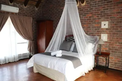 a bedroom with a bed with a mosquito net at Sundowners Game Lodge in Marble Hall