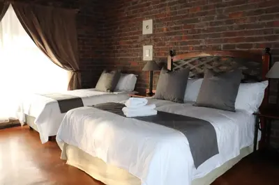 two beds in a room with a brick wall at Sundowners Game Lodge in Marble Hall